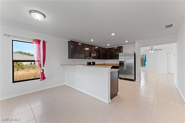 kitchen with dark brown cabinetry, stainless steel fridge, kitchen peninsula, and light tile patterned floors