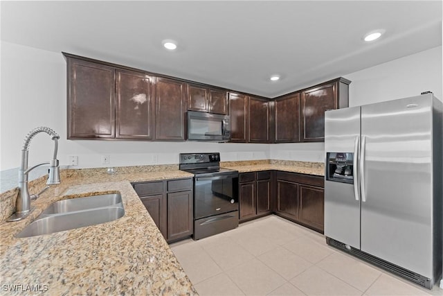 kitchen with dark brown cabinetry, sink, light stone counters, light tile patterned floors, and black appliances