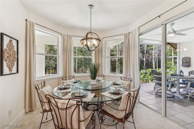 dining room featuring ceiling fan with notable chandelier, plenty of natural light, baseboards, and light tile patterned floors