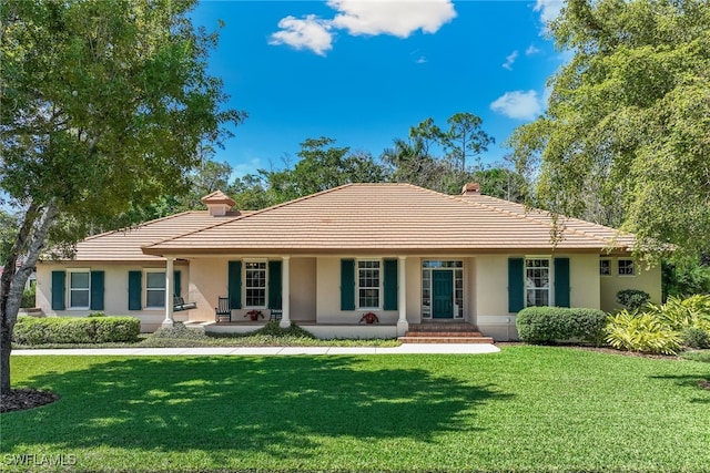 ranch-style home featuring a front lawn, a porch, a tile roof, and stucco siding