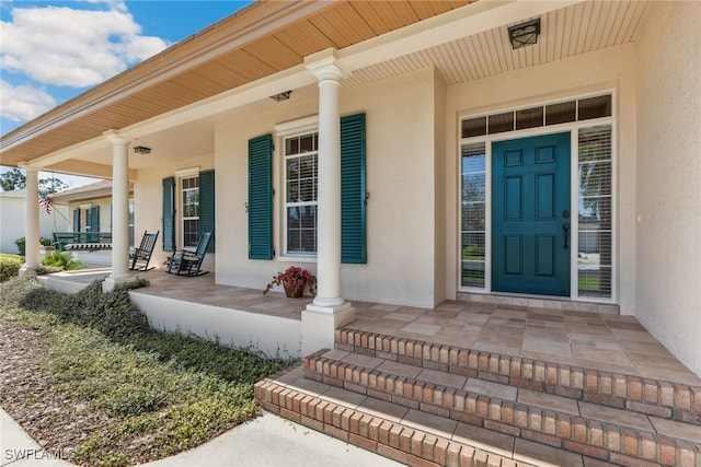 property entrance with covered porch and stucco siding