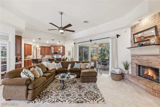 living area featuring light tile patterned floors, ceiling fan, a brick fireplace, and visible vents