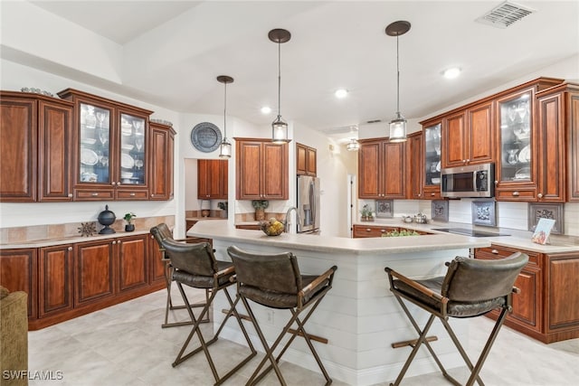 kitchen featuring appliances with stainless steel finishes, light countertops, glass insert cabinets, and a kitchen bar