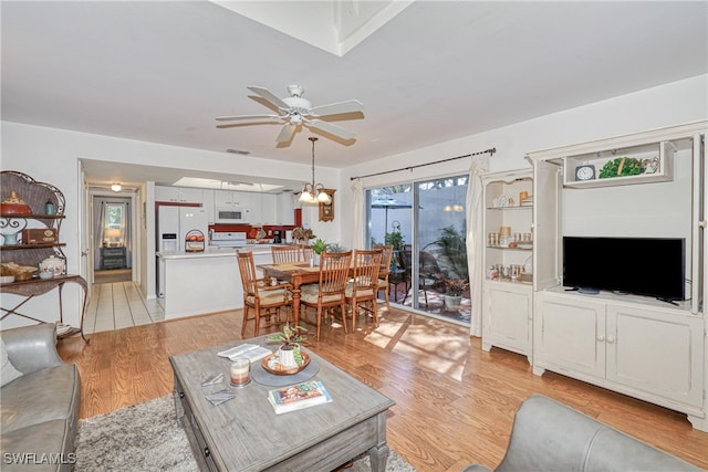 living room with ceiling fan with notable chandelier and light wood-type flooring