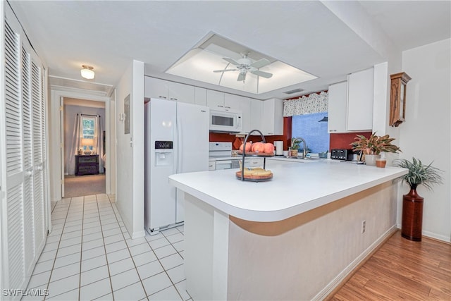 kitchen featuring ceiling fan, white appliances, kitchen peninsula, and white cabinets