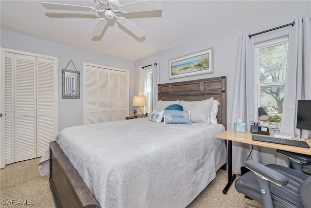 carpeted bedroom featuring multiple closets and ceiling fan