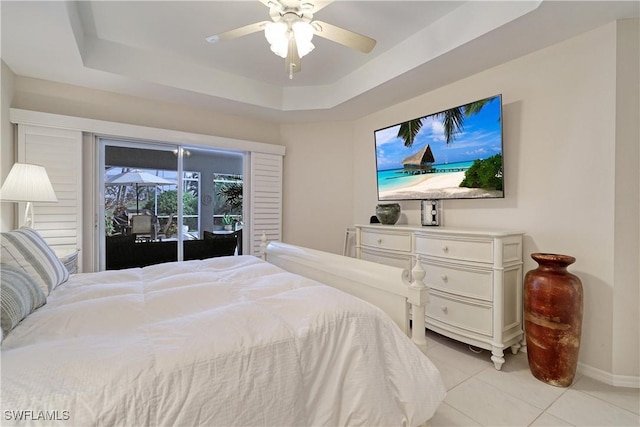 bedroom featuring light tile patterned flooring, ceiling fan, a tray ceiling, and access to outside