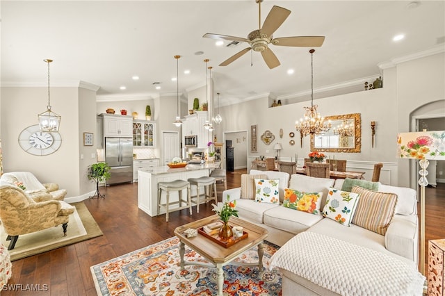 living room with dark wood-type flooring, crown molding, and ceiling fan with notable chandelier