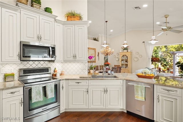 kitchen featuring appliances with stainless steel finishes, decorative light fixtures, lofted ceiling, white cabinets, and backsplash