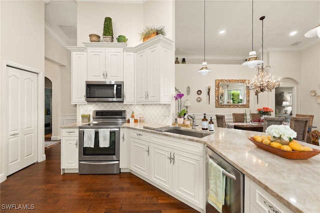 kitchen featuring pendant lighting, sink, crown molding, white cabinetry, and stainless steel appliances