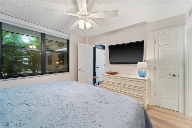 bedroom featuring ceiling fan, light hardwood / wood-style floors, and a textured ceiling