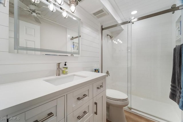 bathroom featuring toilet, a shower with shower door, vanity, wooden walls, and hardwood / wood-style flooring