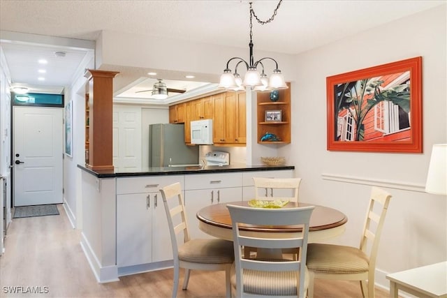 kitchen featuring ceiling fan with notable chandelier, decorative light fixtures, white cabinetry, stainless steel fridge, and light wood-type flooring