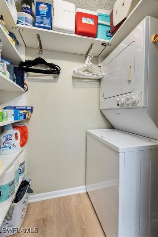 laundry area featuring stacked washing maching and dryer and light hardwood / wood-style floors