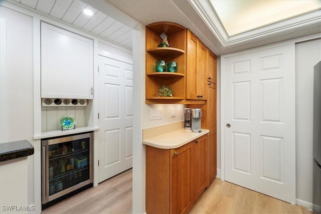 bar with beverage cooler and light hardwood / wood-style flooring