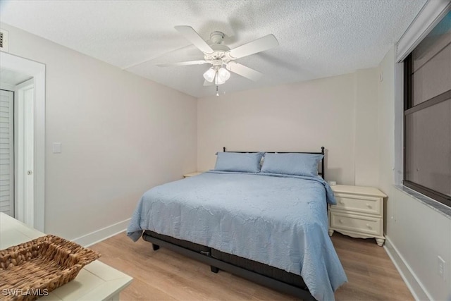 bedroom featuring ceiling fan, light hardwood / wood-style flooring, and a textured ceiling