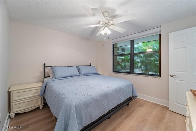 bedroom featuring ceiling fan, a textured ceiling, and light hardwood / wood-style flooring