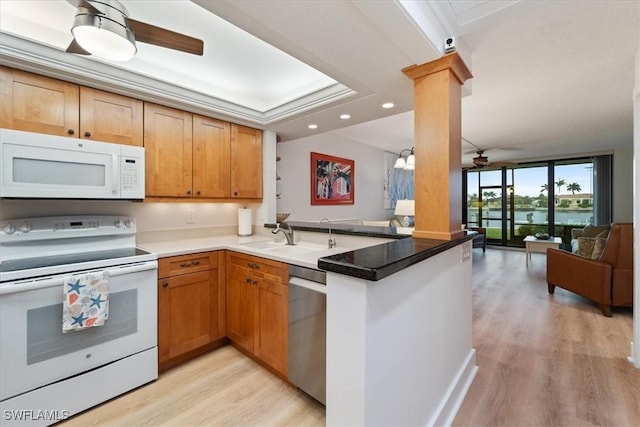 kitchen featuring decorative columns, sink, light hardwood / wood-style floors, kitchen peninsula, and white appliances