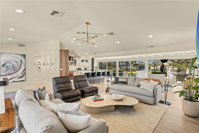 living room with lofted ceiling, a notable chandelier, and light wood-type flooring