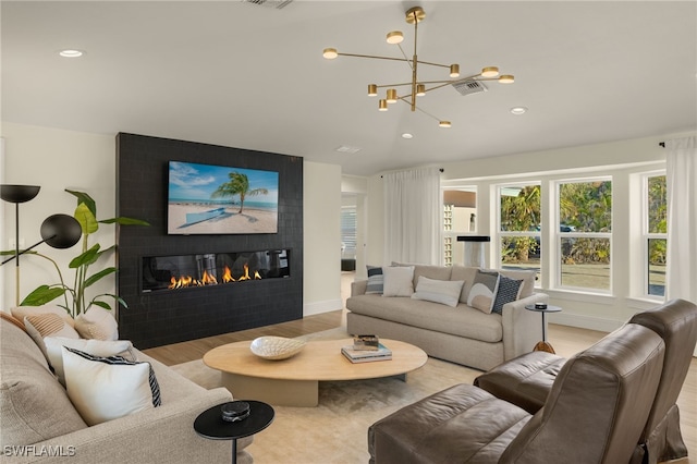 living room with a chandelier, a fireplace, and light hardwood / wood-style floors