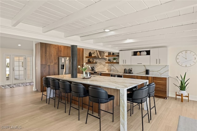 kitchen with a breakfast bar, stainless steel appliances, tasteful backsplash, white cabinets, and a kitchen island