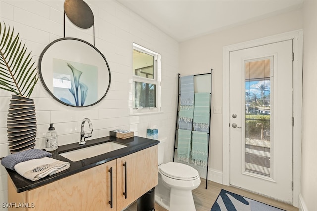 bathroom featuring vanity, hardwood / wood-style floors, tile walls, and toilet