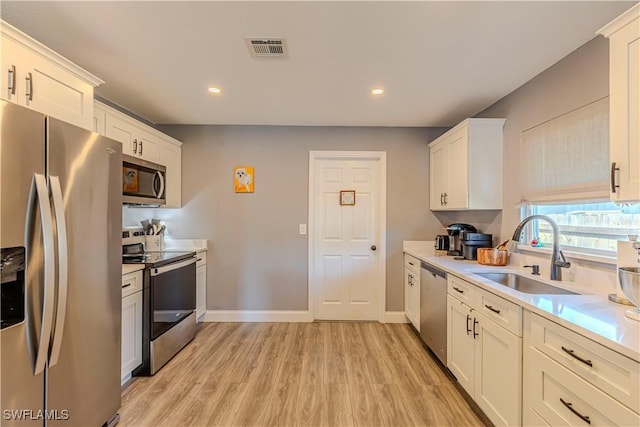 kitchen featuring sink, light wood-type flooring, white cabinets, and appliances with stainless steel finishes