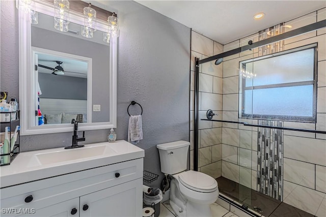 bathroom with a shower with door, vanity, ceiling fan, and toilet