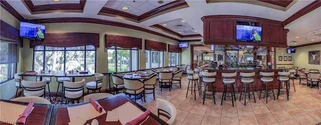 interior space with coffered ceiling, light tile patterned floors, and ornamental molding