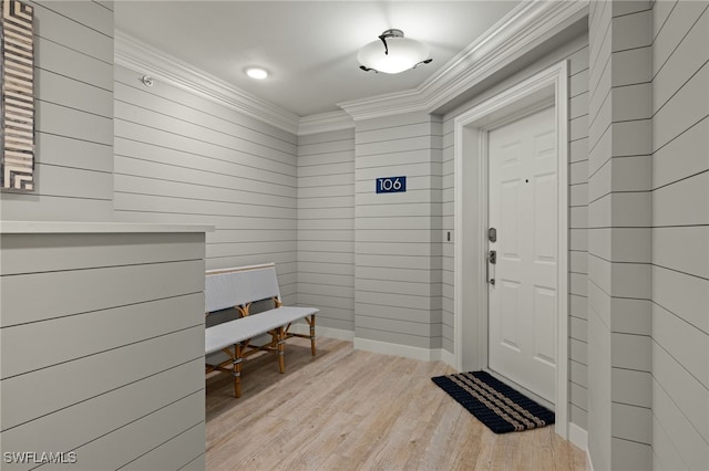 mudroom with ornamental molding, wooden walls, and light hardwood / wood-style floors