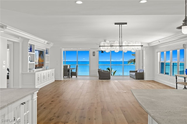 unfurnished living room with crown molding, light hardwood / wood-style flooring, a chandelier, and a water view