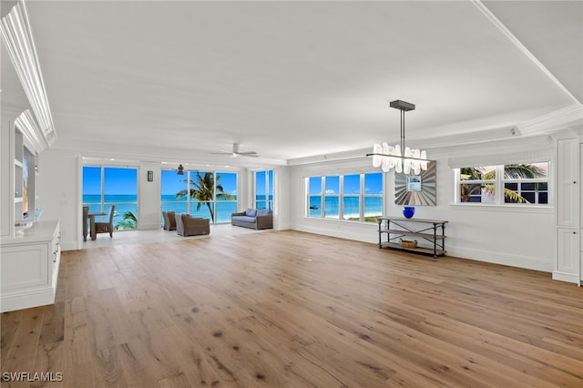 unfurnished living room featuring ornamental molding, a water view, ceiling fan with notable chandelier, and light hardwood / wood-style flooring