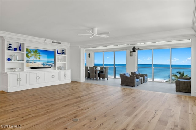 unfurnished living room featuring crown molding, ceiling fan, built in shelves, and light hardwood / wood-style flooring