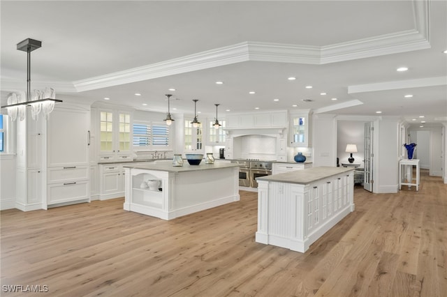 kitchen with a spacious island, white cabinetry, crown molding, and pendant lighting