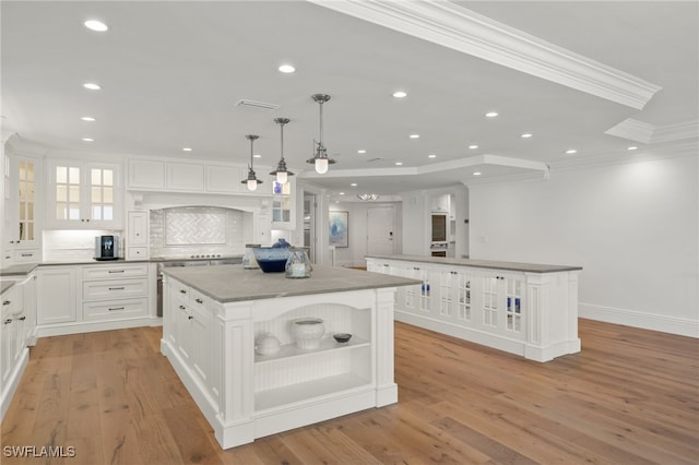 kitchen with white cabinetry, hanging light fixtures, ornamental molding, and a center island