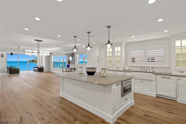 kitchen featuring stainless steel microwave, hanging light fixtures, a kitchen island, and white cabinets