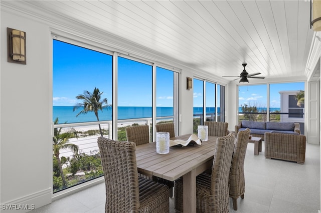 sunroom / solarium featuring a water view, wood ceiling, ceiling fan, and a view of the beach