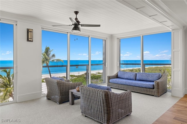 sunroom with a water view, ceiling fan, and a view of the beach