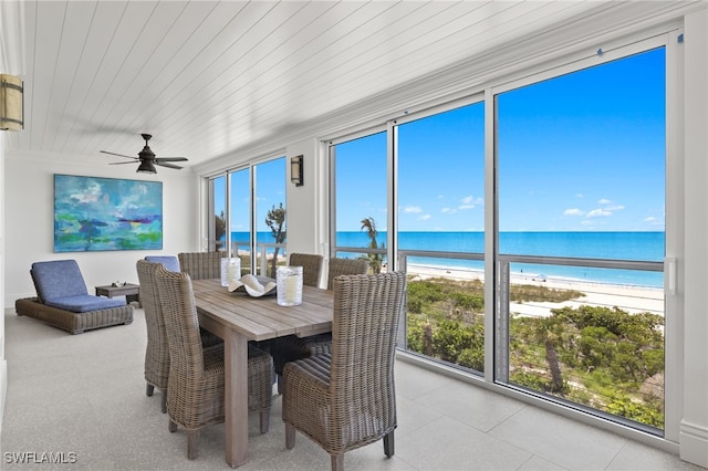 sunroom / solarium with a water view, ceiling fan, a beach view, and wooden ceiling