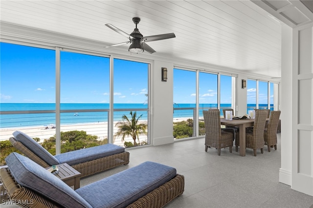 sunroom with a water view, a beach view, and ceiling fan