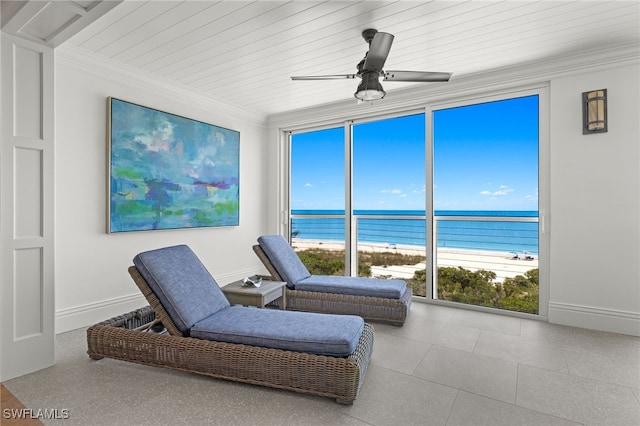 interior space with a view of the beach, crown molding, ceiling fan, a water view, and expansive windows