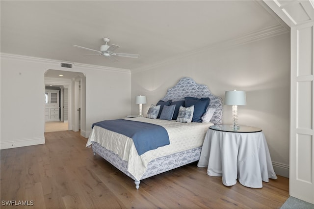 bedroom featuring crown molding, wood-type flooring, and ceiling fan