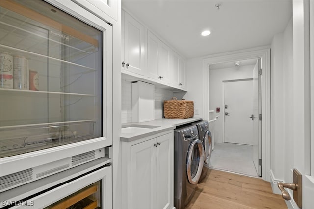 washroom featuring sink, cabinets, washing machine and clothes dryer, and light wood-type flooring