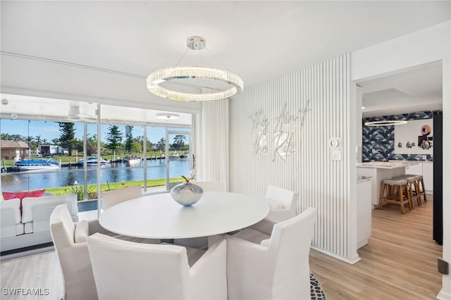 dining space with light hardwood / wood-style flooring and a water view