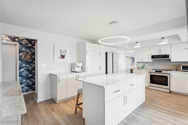 kitchen with white cabinetry, decorative light fixtures, stainless steel appliances, and a kitchen island