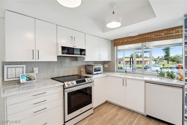 kitchen with sink, white cabinets, stainless steel electric range oven, decorative backsplash, and a raised ceiling