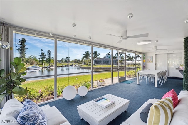 sunroom featuring plenty of natural light, ceiling fan, and a water view