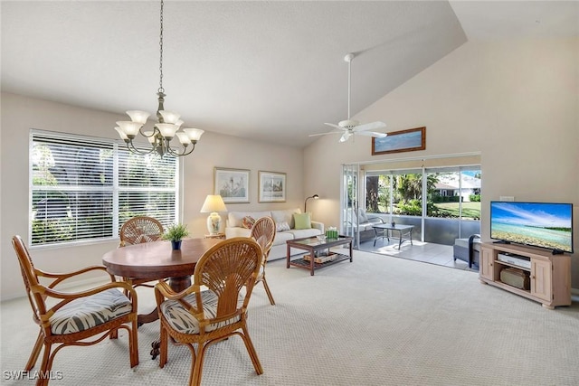 carpeted dining space with ceiling fan with notable chandelier and high vaulted ceiling