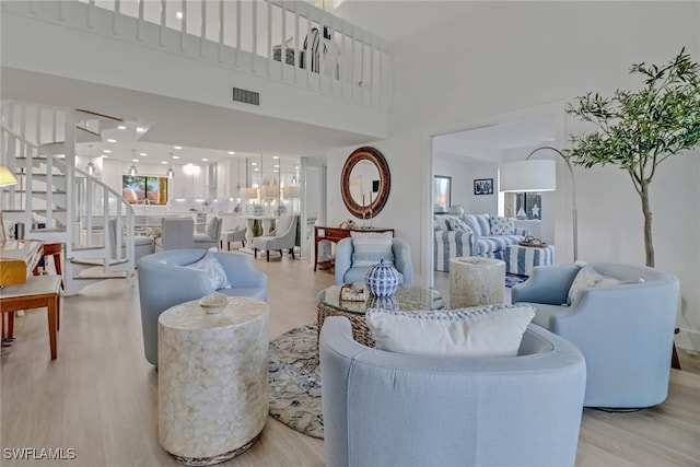 living room featuring a towering ceiling and light hardwood / wood-style flooring