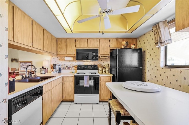 kitchen with black appliances, wallpapered walls, light countertops, and a sink